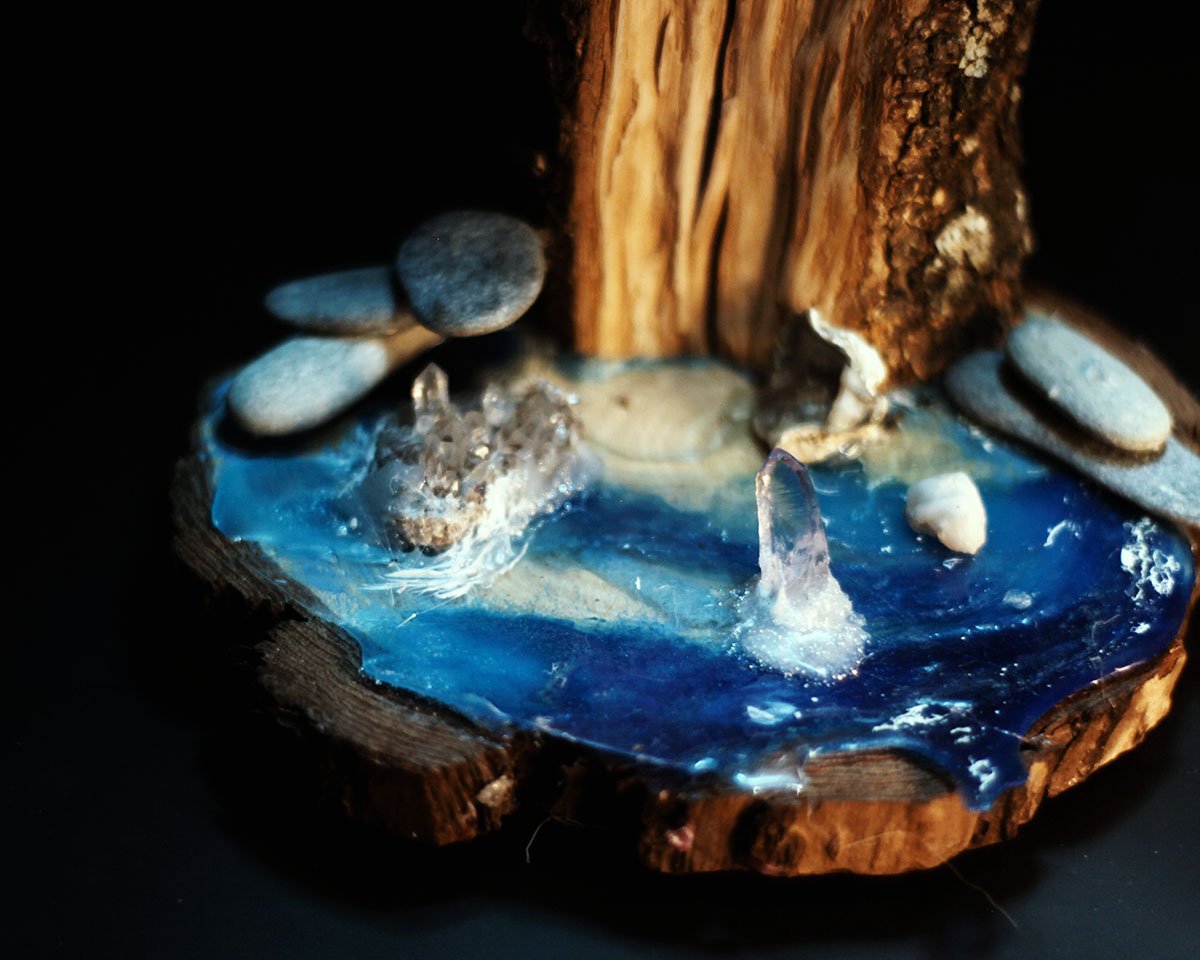 Base de lámpara artesanal con madera, piedras y resina epoxi de color azul.